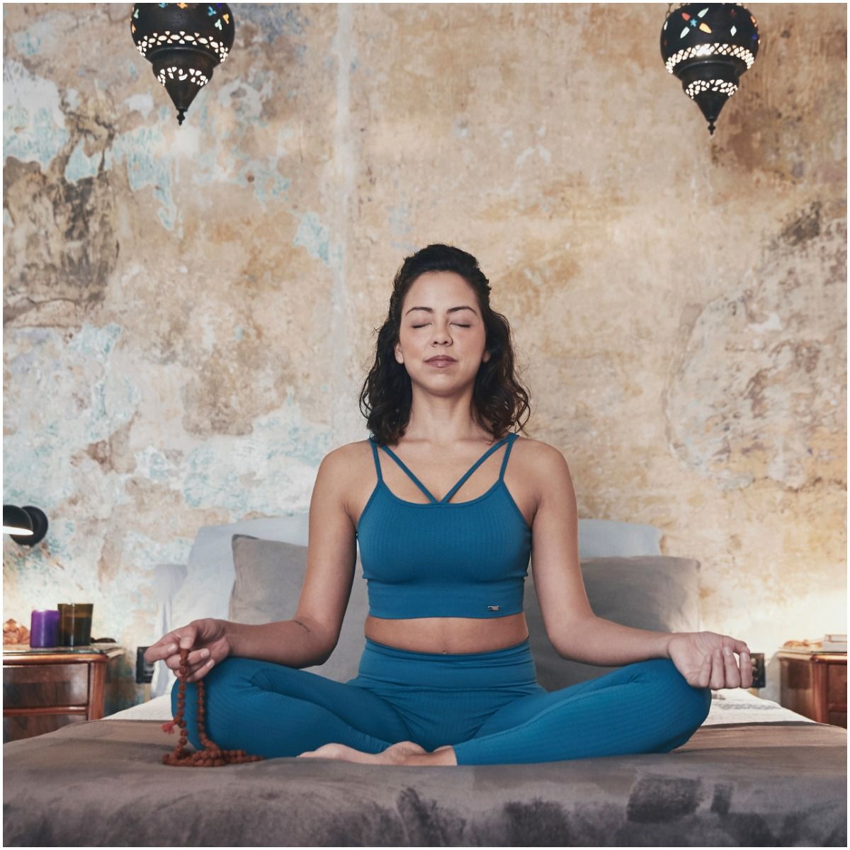 woman chanting a mantra with a mala in hand