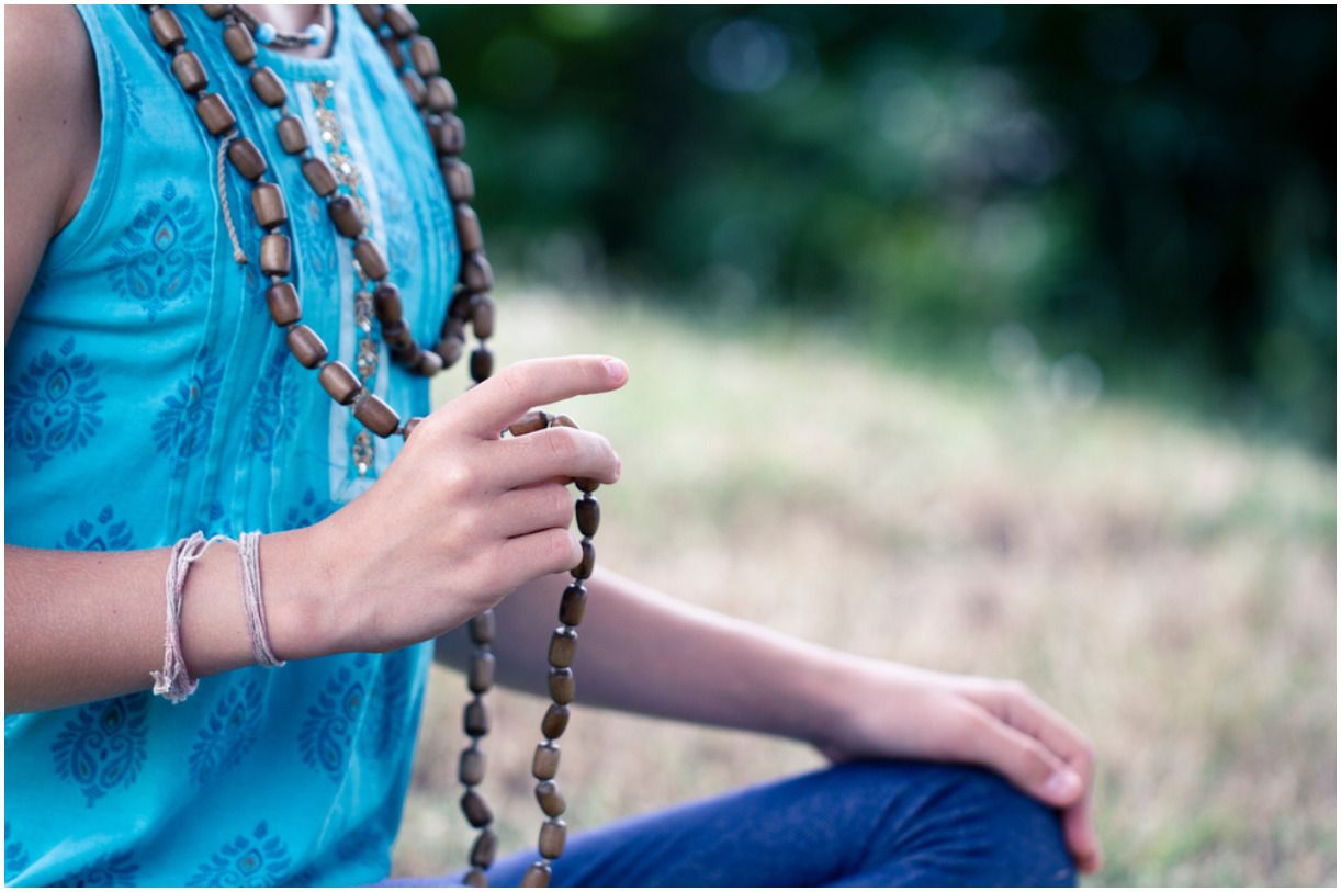 woman chants a mantra on a rosary